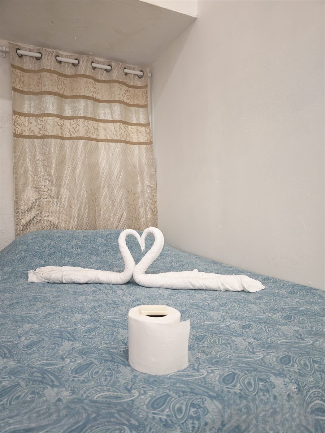 Habitación con camas vestidas, cortinas y ventilador